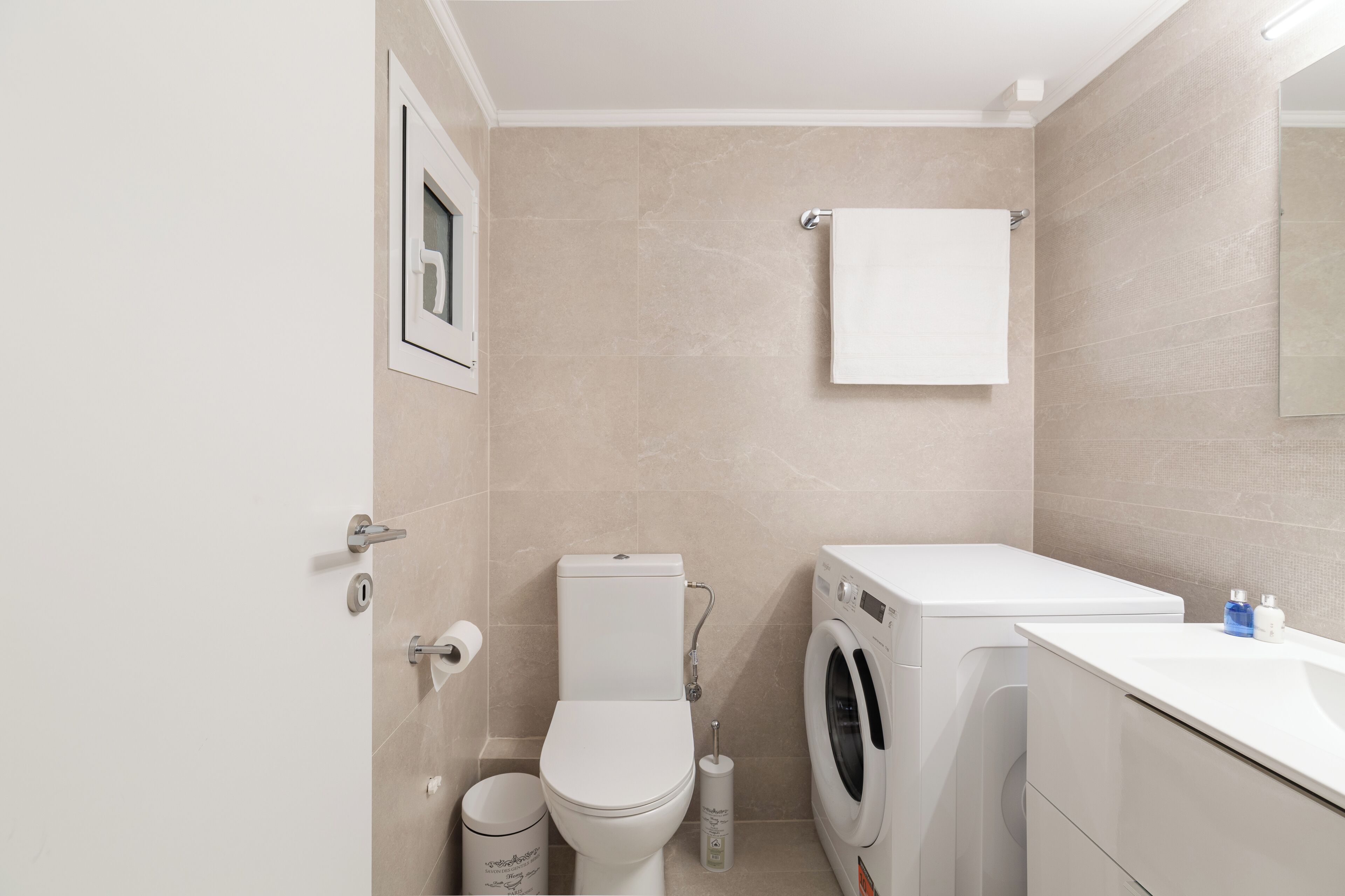 A modern bathroom with a toilet, washing machine, and sink.