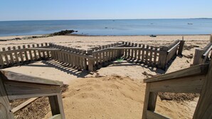 Eine Holzdielen-Strandbegrenzung mit Sandstrand und ruhiger See im Hintergrund.