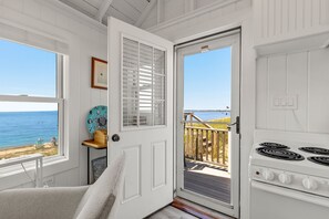 A coastal room with a view of the sea, a white stove, and a door leading to an outdoor deck.