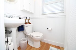 A bathroom with a white sink, toilet, and wooden floor.