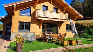 Une cabane en bois dotée d’un balcon, d’un espace salon extérieur et d’un jardin.