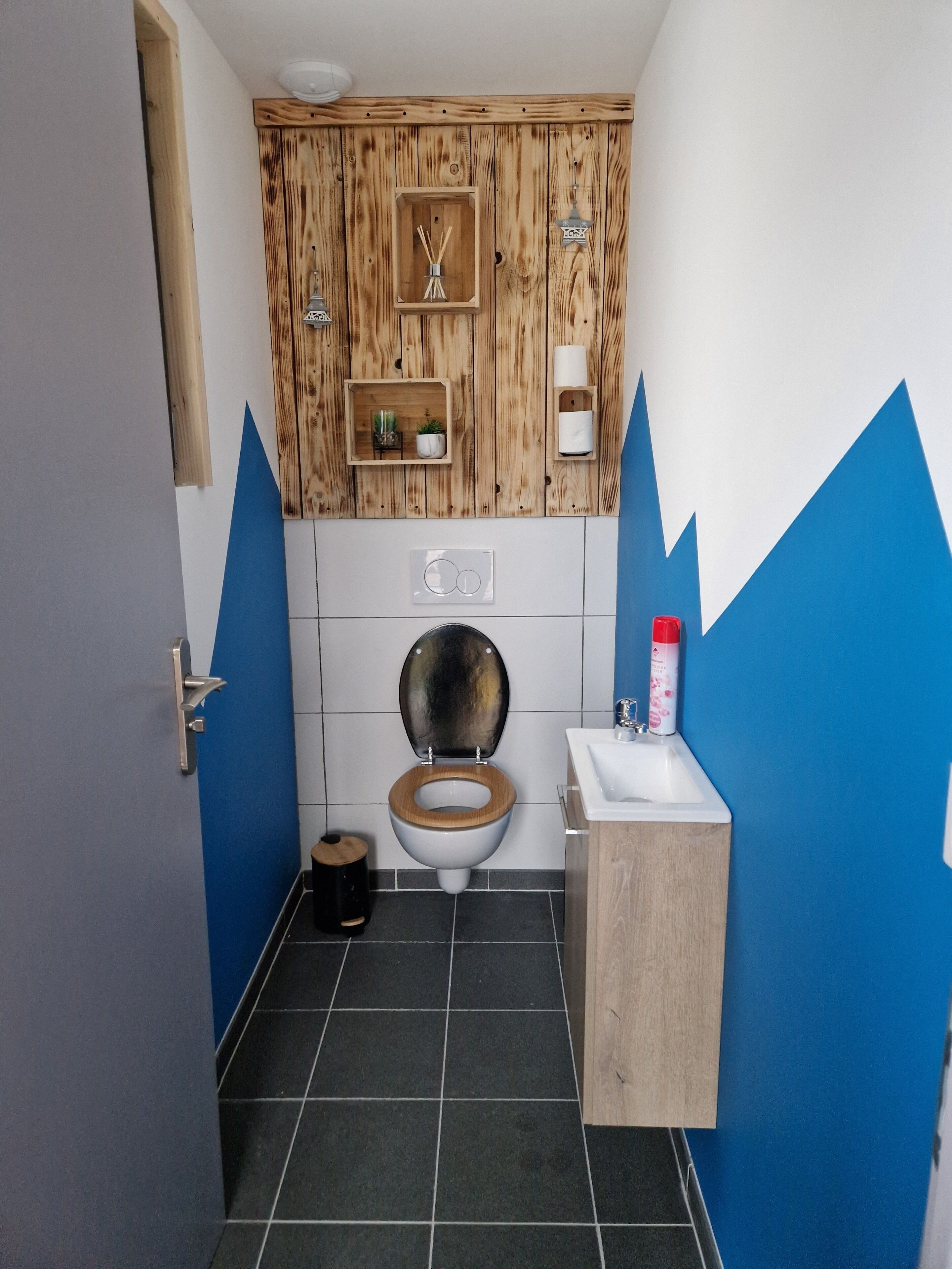 A bathroom with a wooden vanity, a toilet, and a sink.