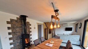 Un salon moderne avec une cheminée en pierre, une table à manger en bois et un escalier menant à un niveau supérieur.