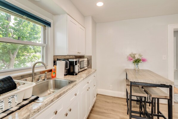 A kitchen with white cabinets, a sink, a coffee maker, and a vase with flowers.