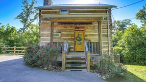 A log cabin with a wooden staircase leading to a yellow door, surrounded by greenery. - Hot Tub + Pool Table: 3-story Gatlinburg Cabin! (Gatlinburg)
