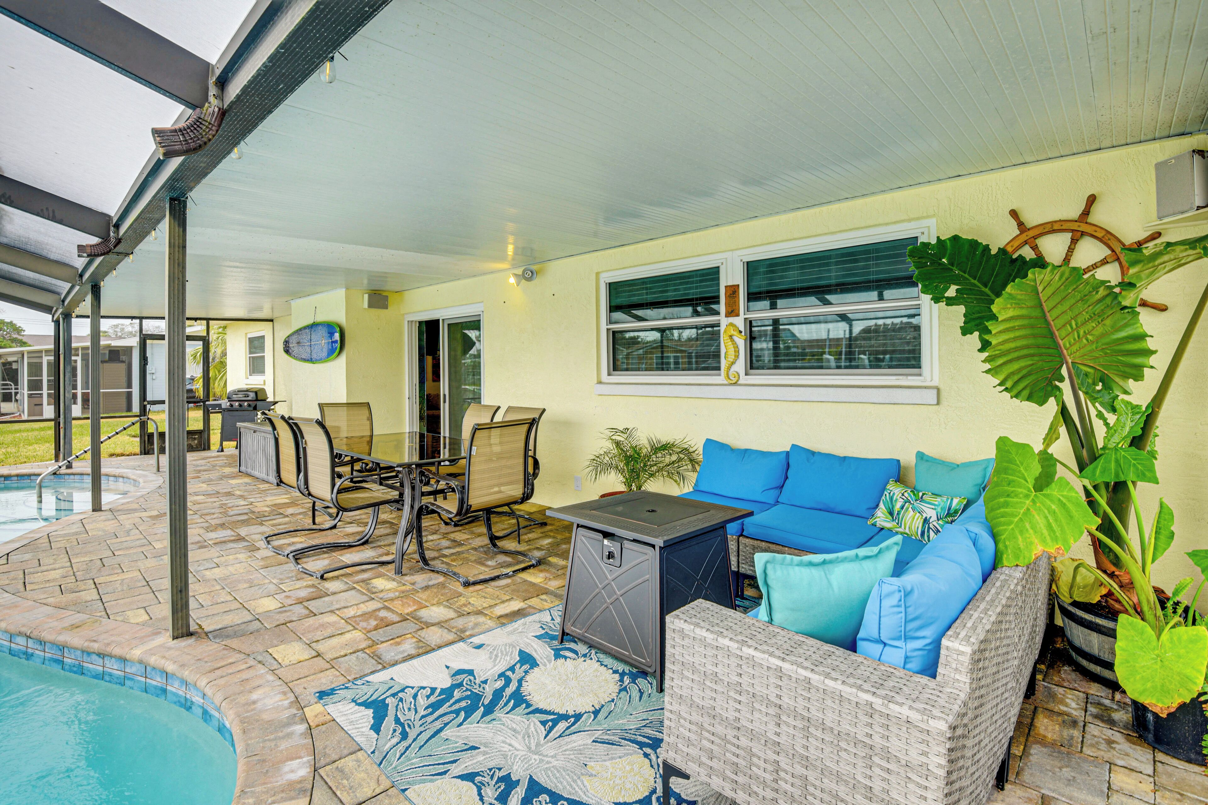 Un patio couvert avec une piscine, du mobilier d’extérieur et une grande plante en pot.