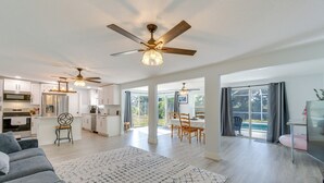 A spacious living area with a modern kitchen, dining area, and large windows providing natural light.