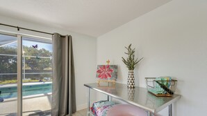 A modern room with a glass door leading to a pool, a metal table with a vase and a picture frame, and a pink inflatable ring on the floor.
