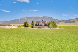 Una casa con un amplio jardín delantero y montañas al fondo.