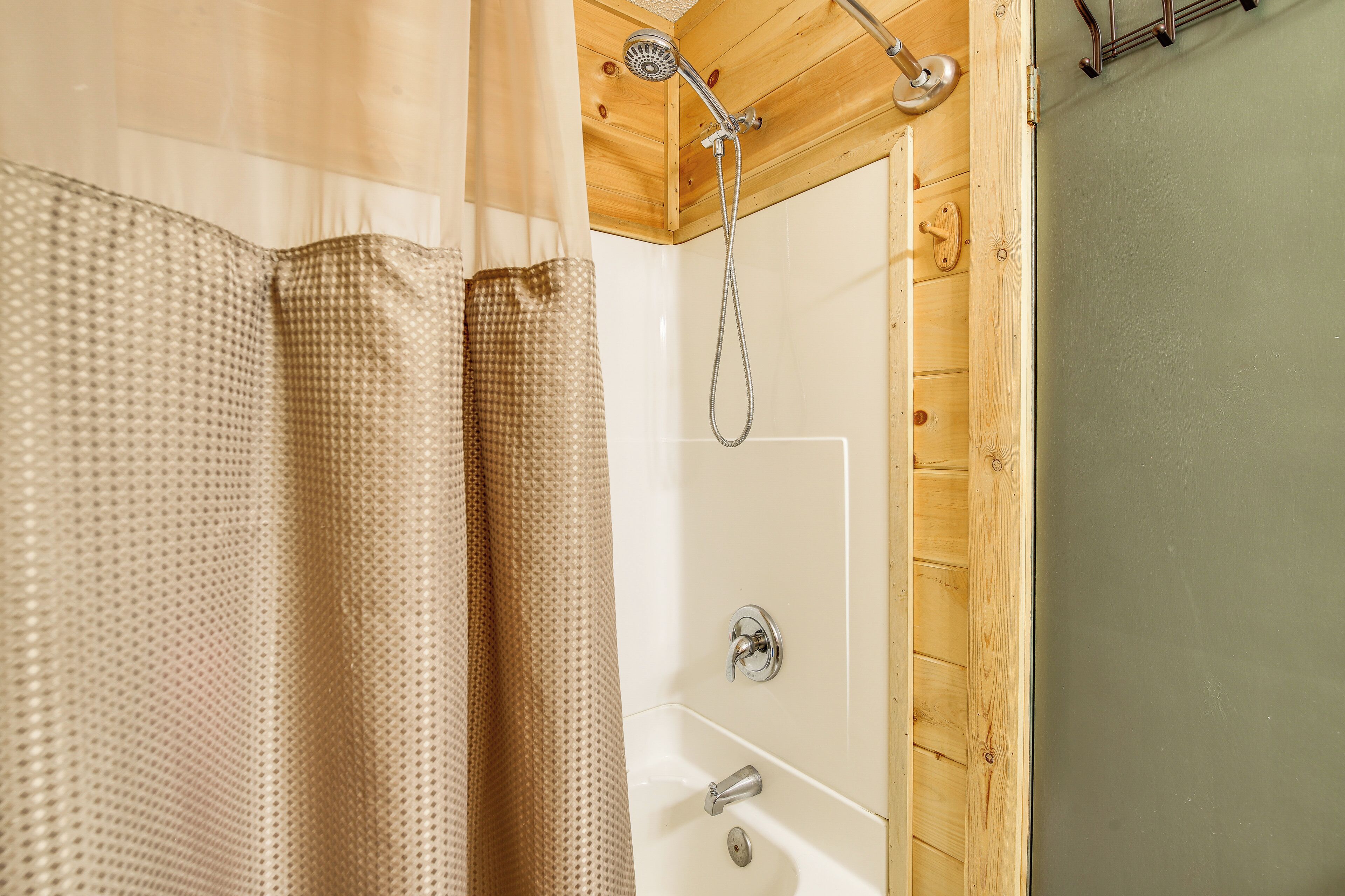 Un interior de madera con ducha, bañera y una cortina.