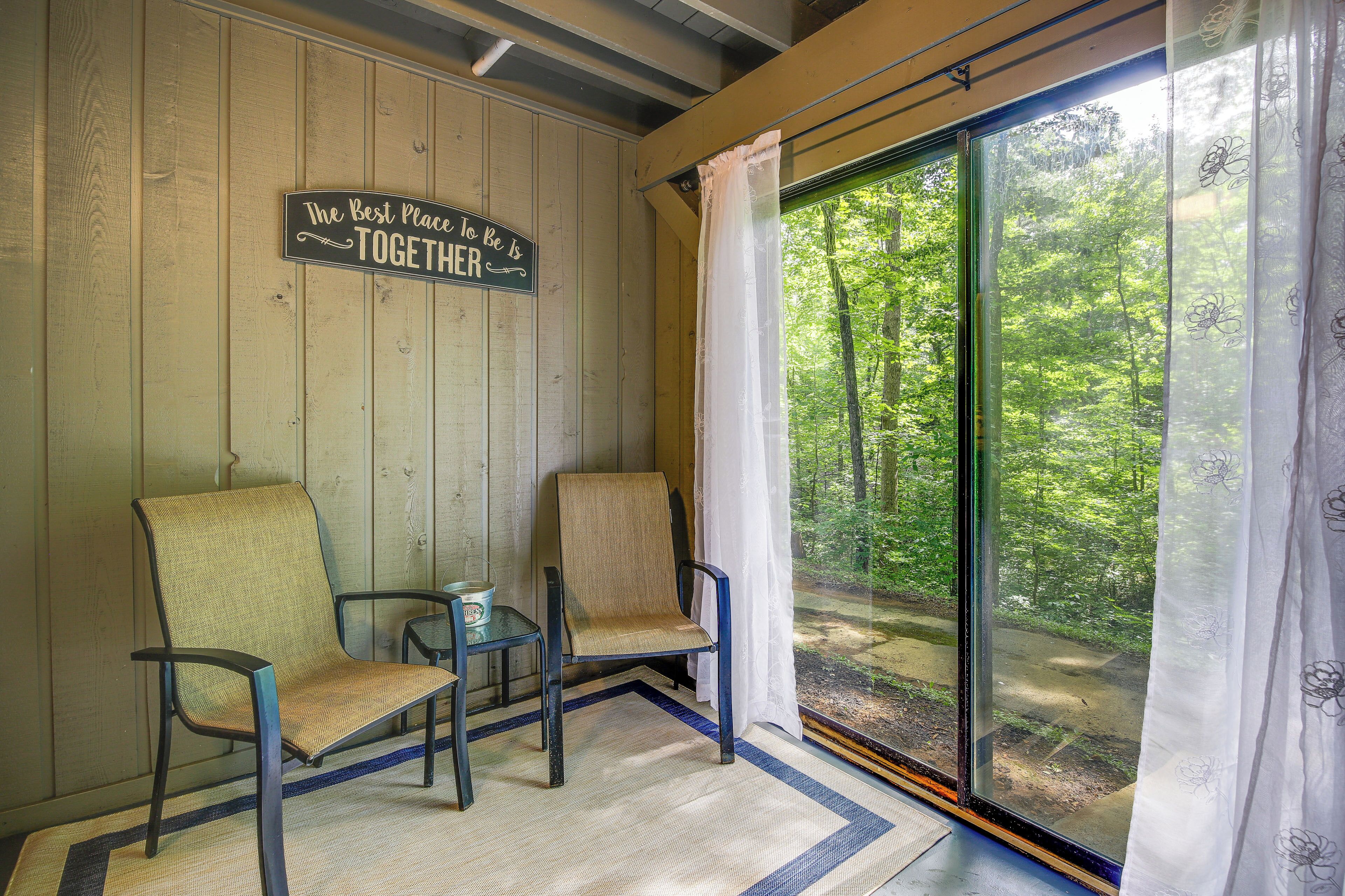 A cozy room with a large window, two chairs, a small table, and a sign on the wall.