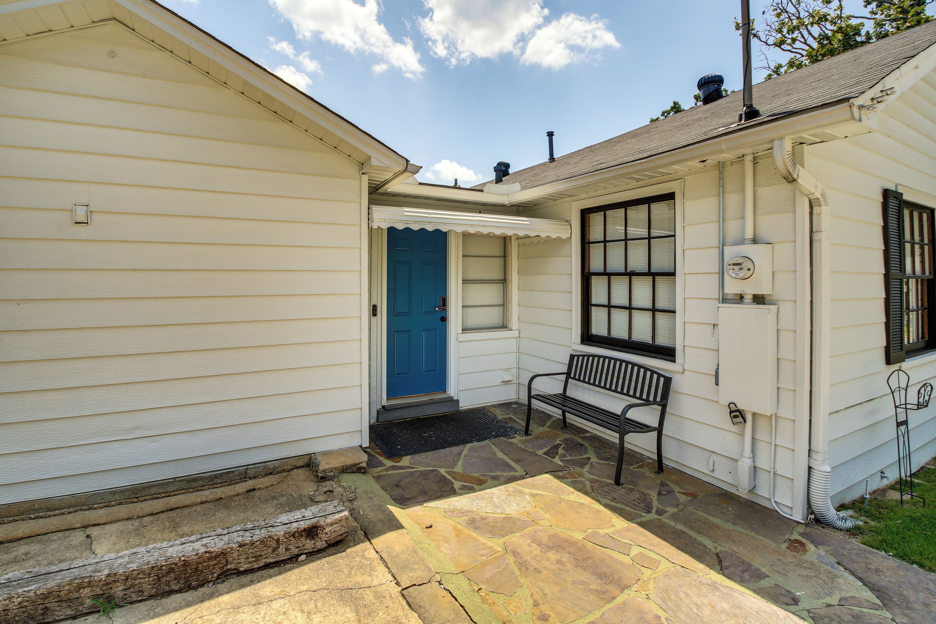 A house with a blue door, a stone patio, and a bench.