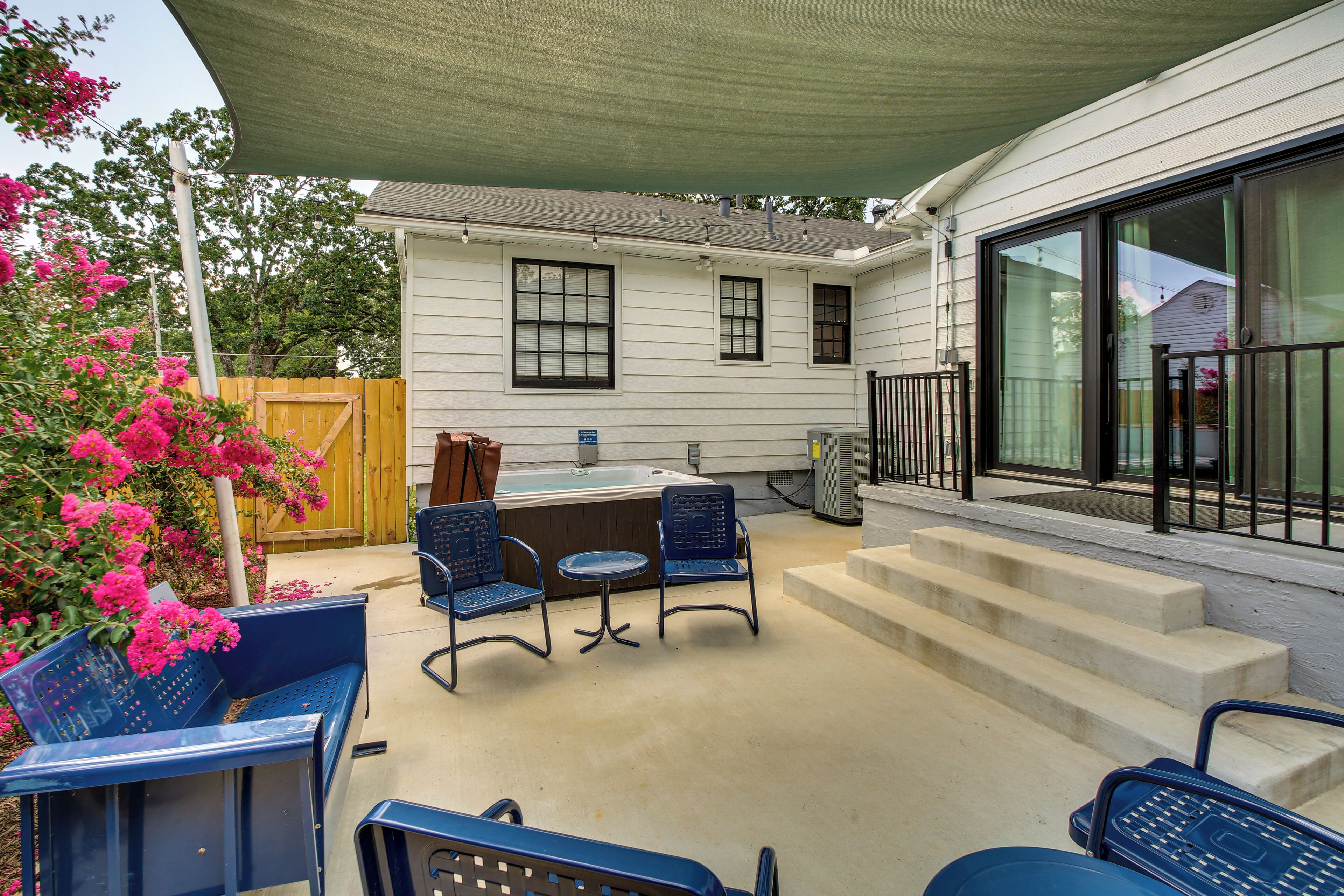 A covered patio with outdoor seating, a hot tub, and a wooden fence.