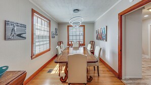 Una sala menjador amb una taula de fusta llarga, sis cadires i una làmpada penjant moderna.