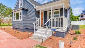 A single-story house with a front porch, a small set of steps, and a flag.