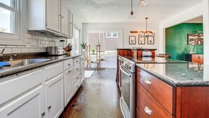 A kitchen with white cabinets, a granite countertop, and a wooden island. - 2 Mi to Dtwn Oshkosh: Canal Front w/ Dock! (Oshkosh)