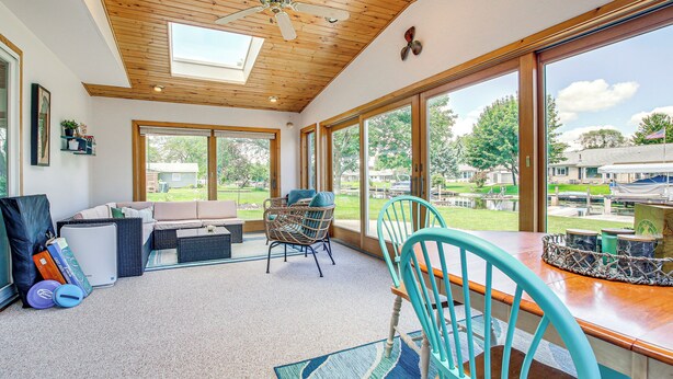 A spacious room with a ceiling fan, large windows, a wooden ceiling, and a view of the outside. - 2 Mi to Dtwn Oshkosh: Canal Front w/ Dock! (Oshkosh)