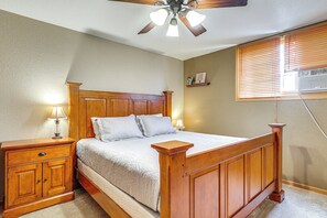 A bedroom with a wooden bed, nightstands, a ceiling fan, and a window with blinds. - Black Hawk Rally Weekend Base w/ Highway Access (Blackhawk)