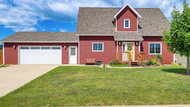 A two-story red house with a white garage door, a front porch, and a well-maintained lawn. - Black Hills Family Home: Close to Hiking Trails! (Blackhawk)