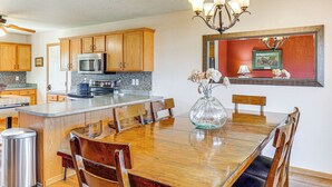A kitchen with wooden cabinets, a microwave, and a dining area with a wooden table and chairs. - Black Hills Family Home: Close to Hiking Trails! (Blackhawk)