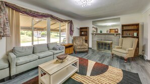 Ein Wohnzimmer mit Sofa, Sesseln, Couchtisch, Kamin und Bücherregal.