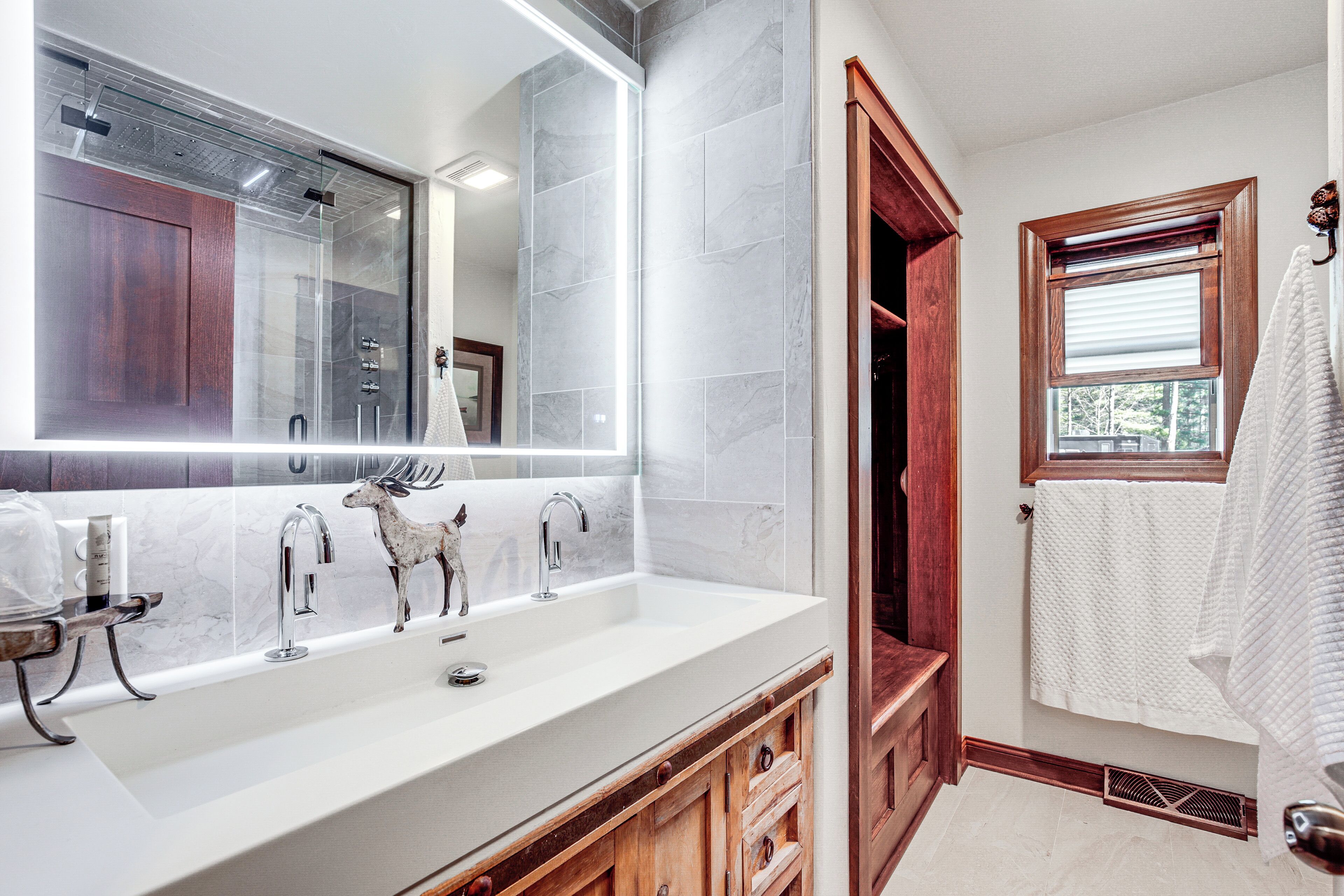Un baño con un espejo grande, un lavabo blanco y un armario de madera.