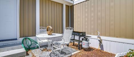 Une terrasse avec une table et des chaises, un tuyau d’arrosage vert et une mangeoire à oiseaux.