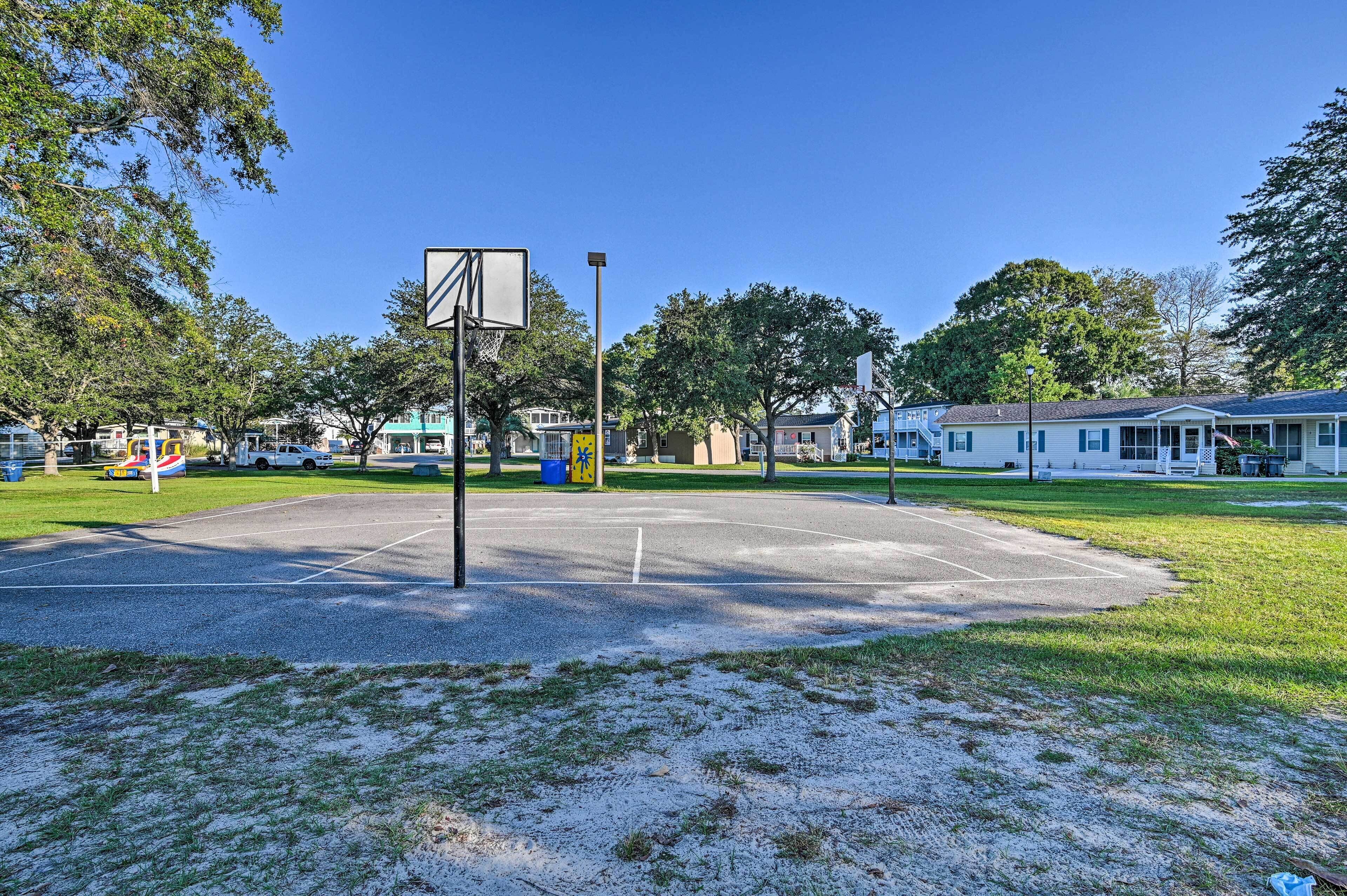 A basketball court with a basketball hoop, surrounded by trees and residential buildings.