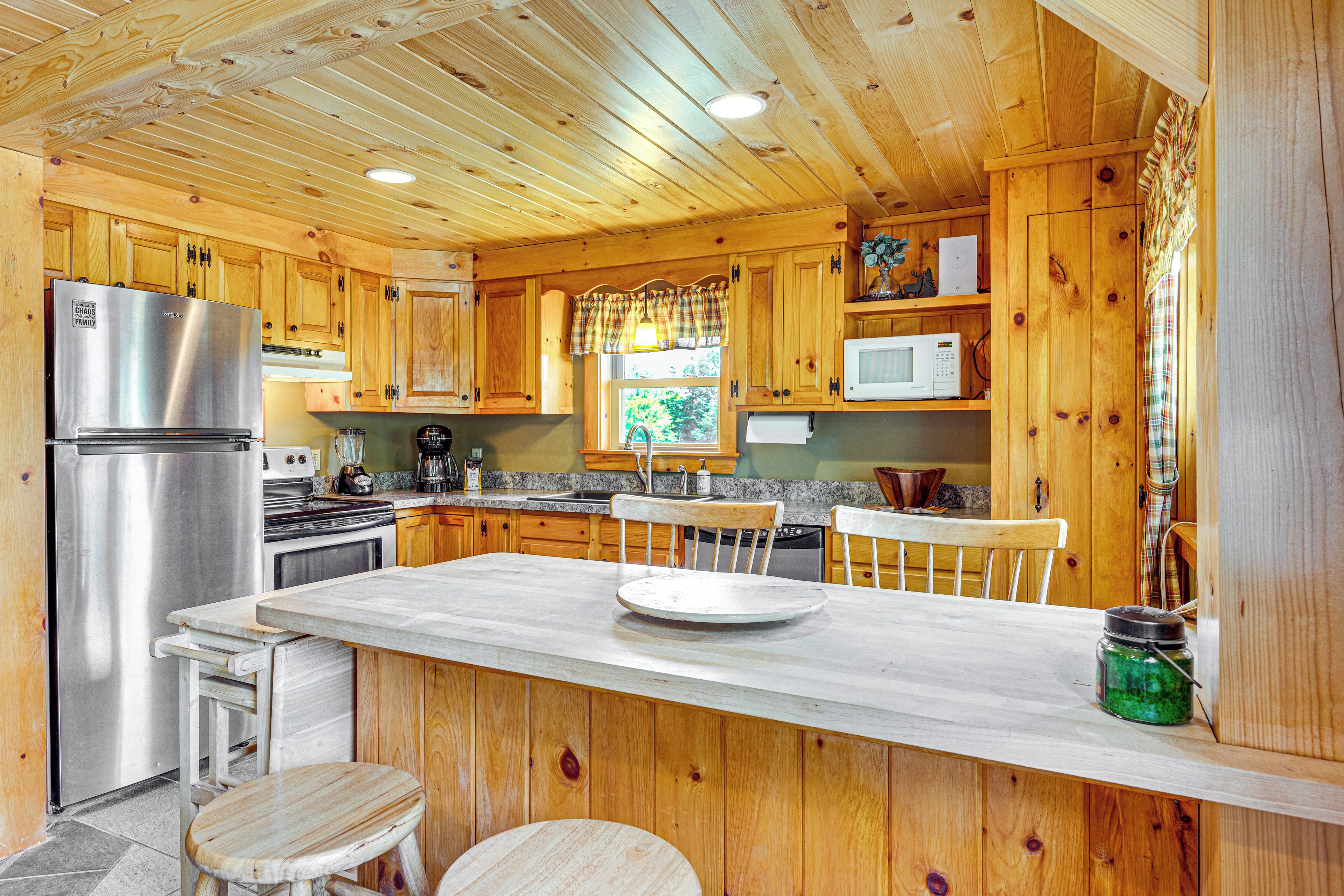 A wooden cabin kitchen with a central island, built-in appliances, and a window with a view.