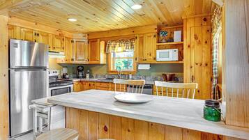A wooden cabin kitchen with a central island, built-in appliances, and a window with a view.