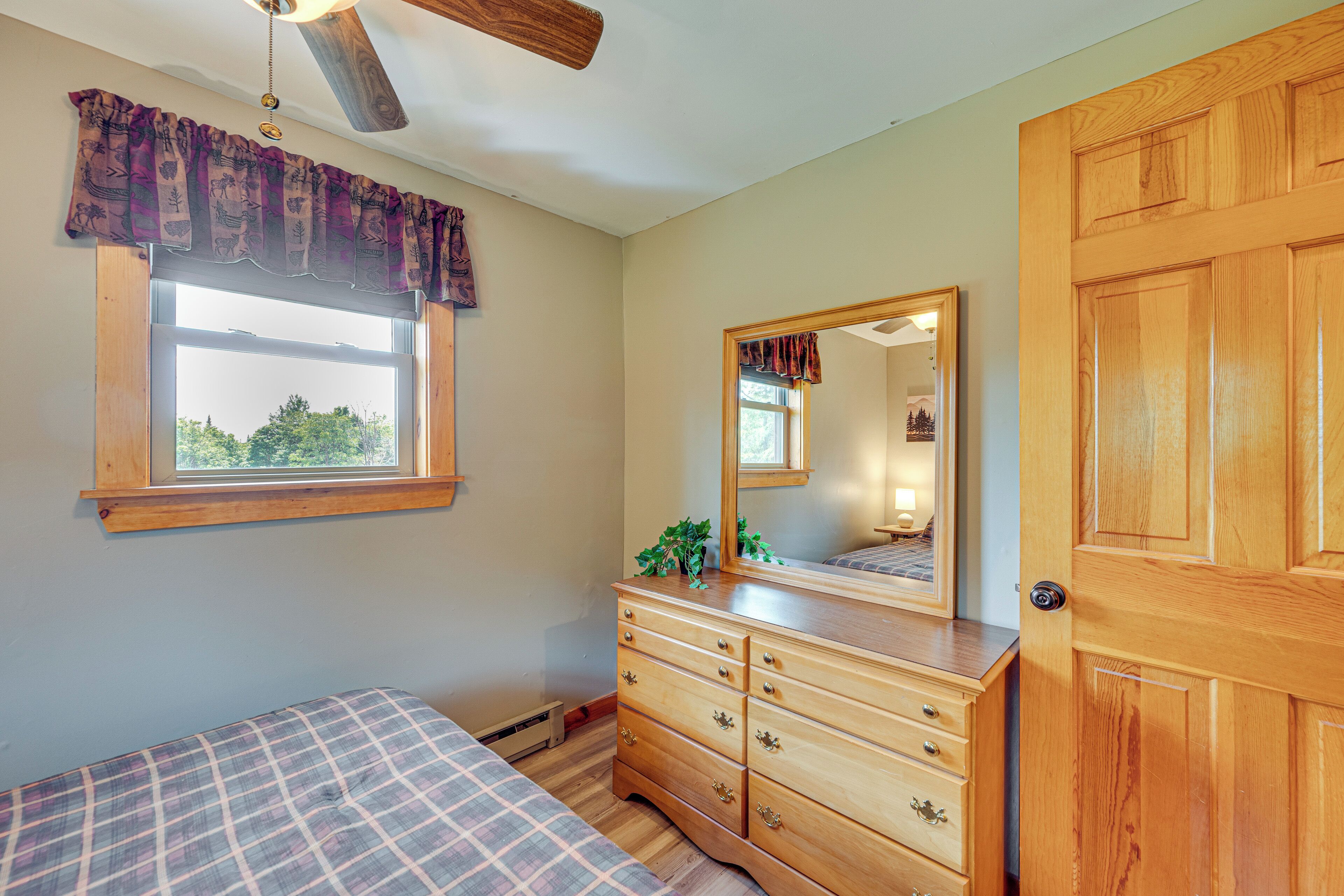 A bedroom with a bed, a dresser, a window, and a door.