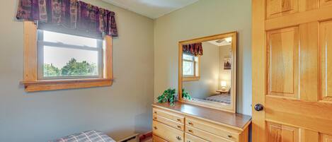 A bedroom with a bed, a dresser, a window, and a door.