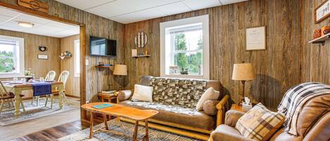 A cozy living room with a wooden wall, a sofa, a coffee table, and a television.