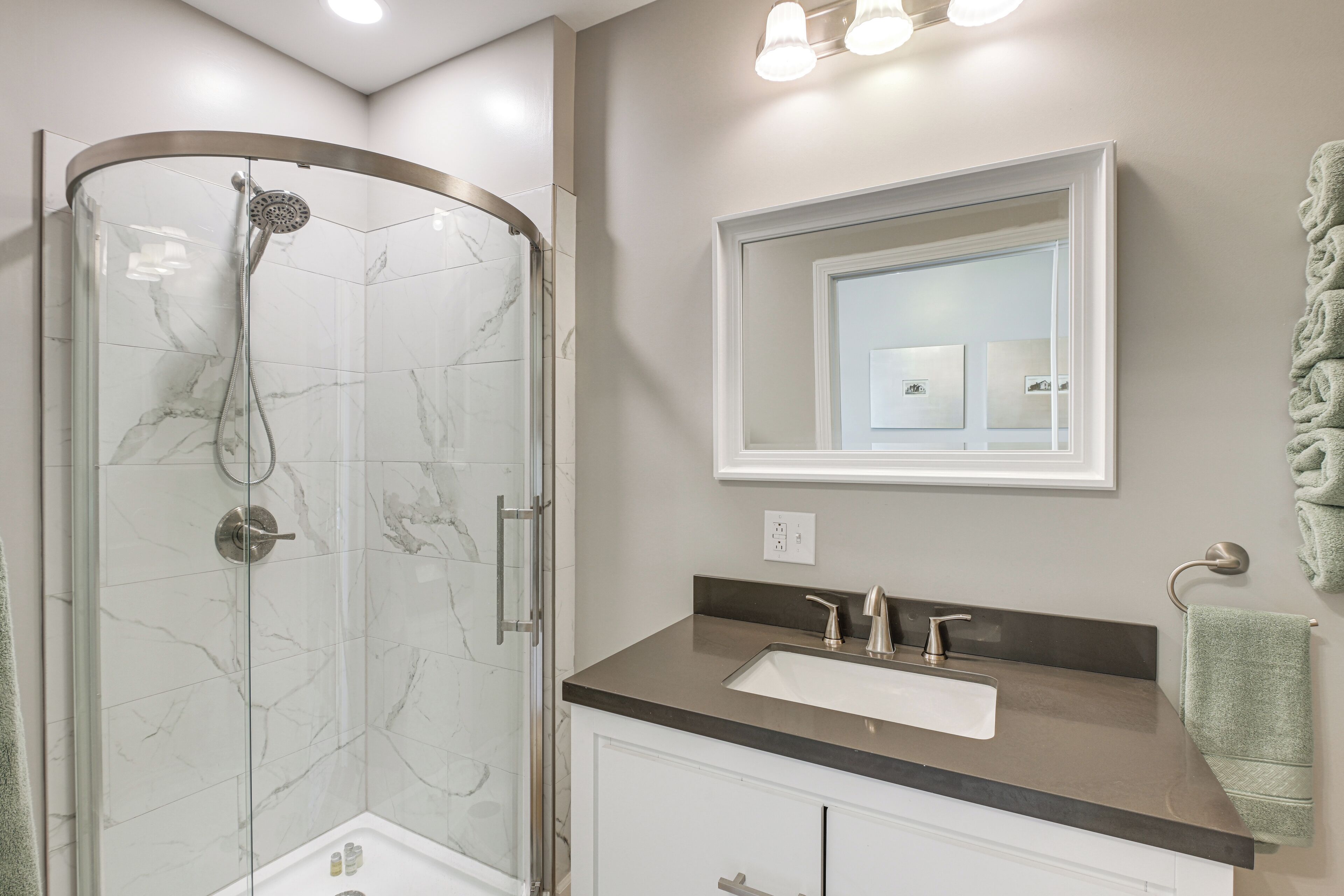 A modern bathroom with a glass-enclosed shower, a vanity with a sink, and a mirror above the vanity.
