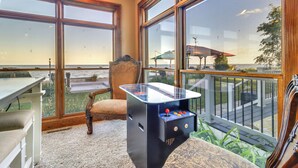 A room with large windows overlooking a deck and the ocean.