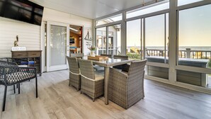 A covered outdoor dining area with wicker furniture, a table, and chairs.