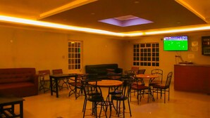 A cozy living room with a flat-screen TV mounted on the wall, a sofa, and a dining area with chairs and tables. - Miriu River Resort (Apoko)