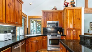 Una cucina con mobili in legno, elettrodomestici in acciaio inossidabile e un piano di lavoro in granito nero.