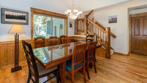 Zona pranzo con tavolo e sedie in legno, un lampadario e una scala.