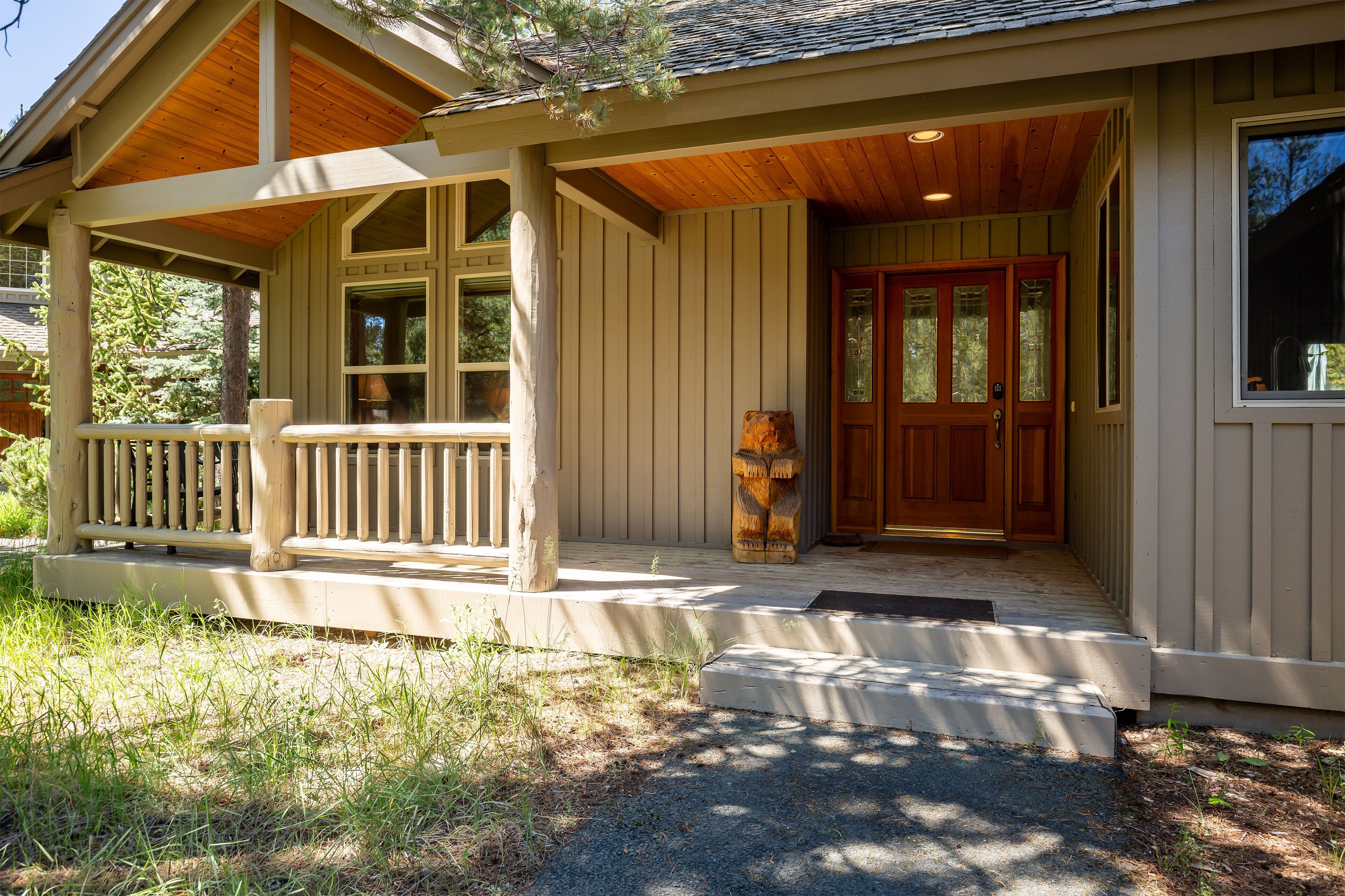 A wooden porch with a bench, a front door with glass panels, and a small step leading to the entrance.