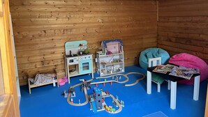 A playroom with wooden walls, a play kitchen, a toy train set, and a bean bag chair. - Haus Im Hochtal - upstairs, 2 bedrooms apartment - small room with 2 single beds (Bad Bleiberg)