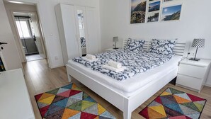 A modern bedroom with a large bed, a wardrobe, a desk, and a chair. - Haus Im Hochtal - upstairs, 2 bedrooms apartment - small room with 2 single beds (Bad Bleiberg)