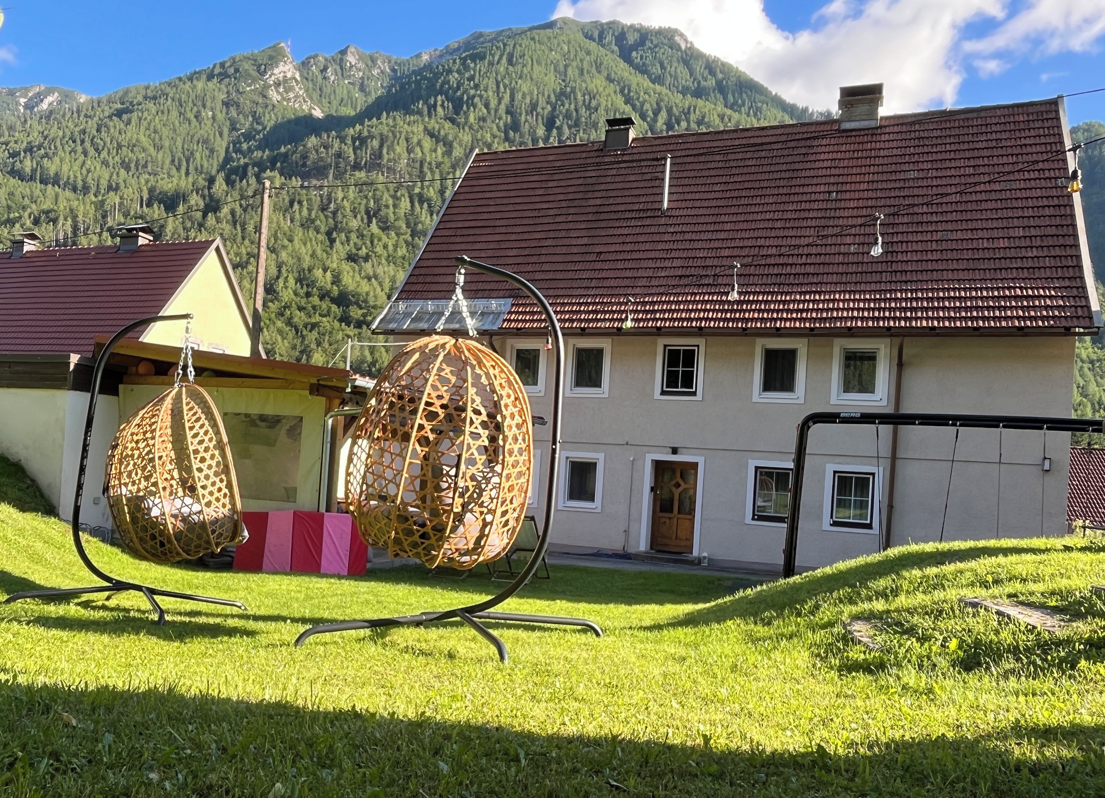 Una casa con tetto in tegole rosse, diverse finestre e una porta. In primo piano, una sedia a dondolo.