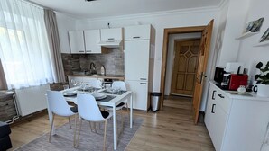 A modern kitchen with white cabinets, a dining area with a table set for four, and a cozy living space with a dark sofa. - UPSTAIRS, 2 BEDROOMS APARTMENT - small room with double bed (Bad Bleiberg)