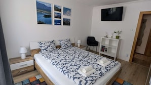 A modern bedroom with a large bed, a TV, a desk, and a chair. - UPSTAIRS, 2 BEDROOMS APARTMENT - small room with double bed (Bad Bleiberg)