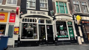 Um bar-hotel com fachada clássica, janelas amplas e um letreiro CBD Bakerhouse bem visível.