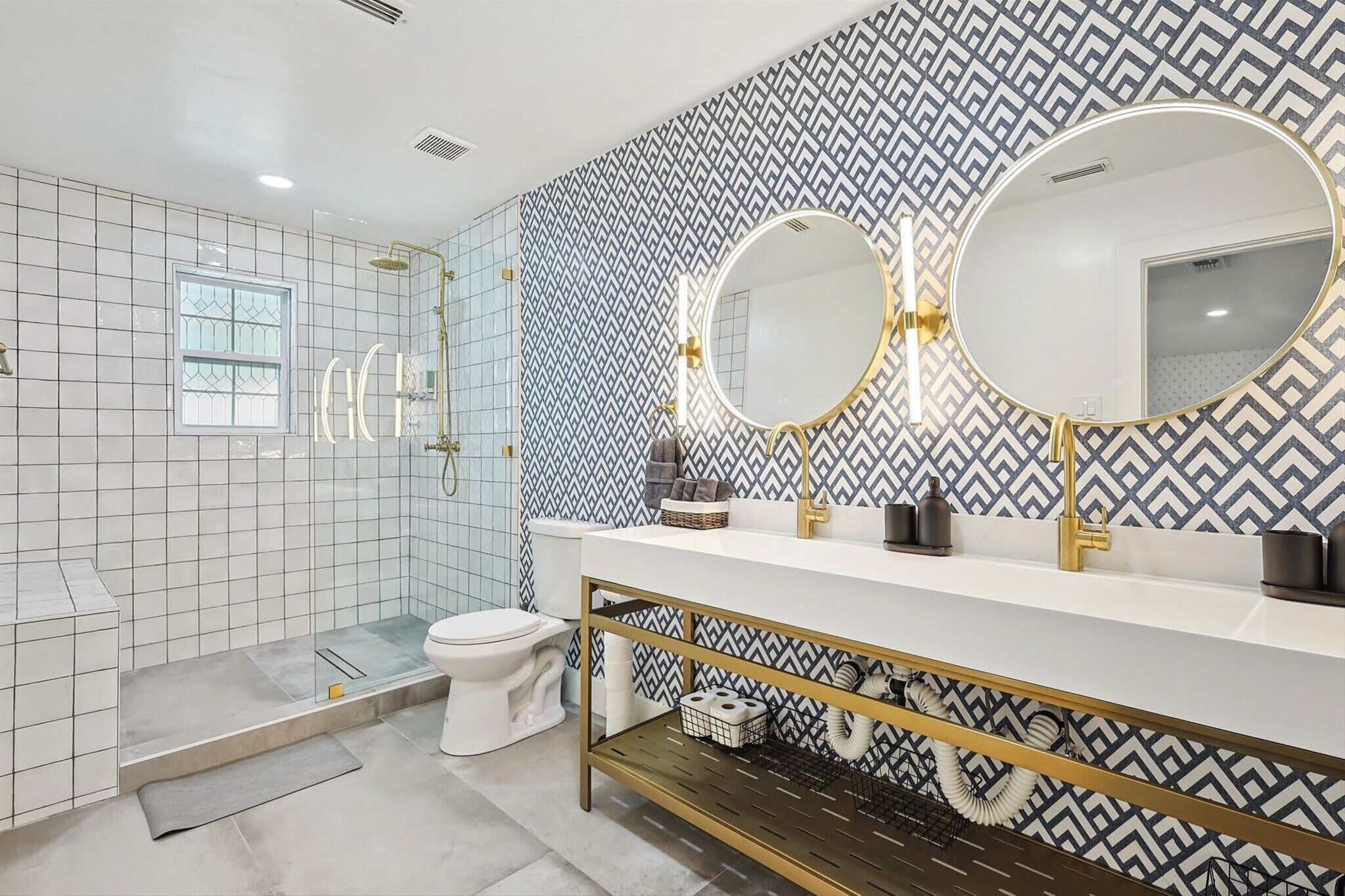 Reminiscent of a Turkish bath, this spa-like bathroom features a spacious glass walk-in shower, dual sinks and mirrors, and essential toiletries.