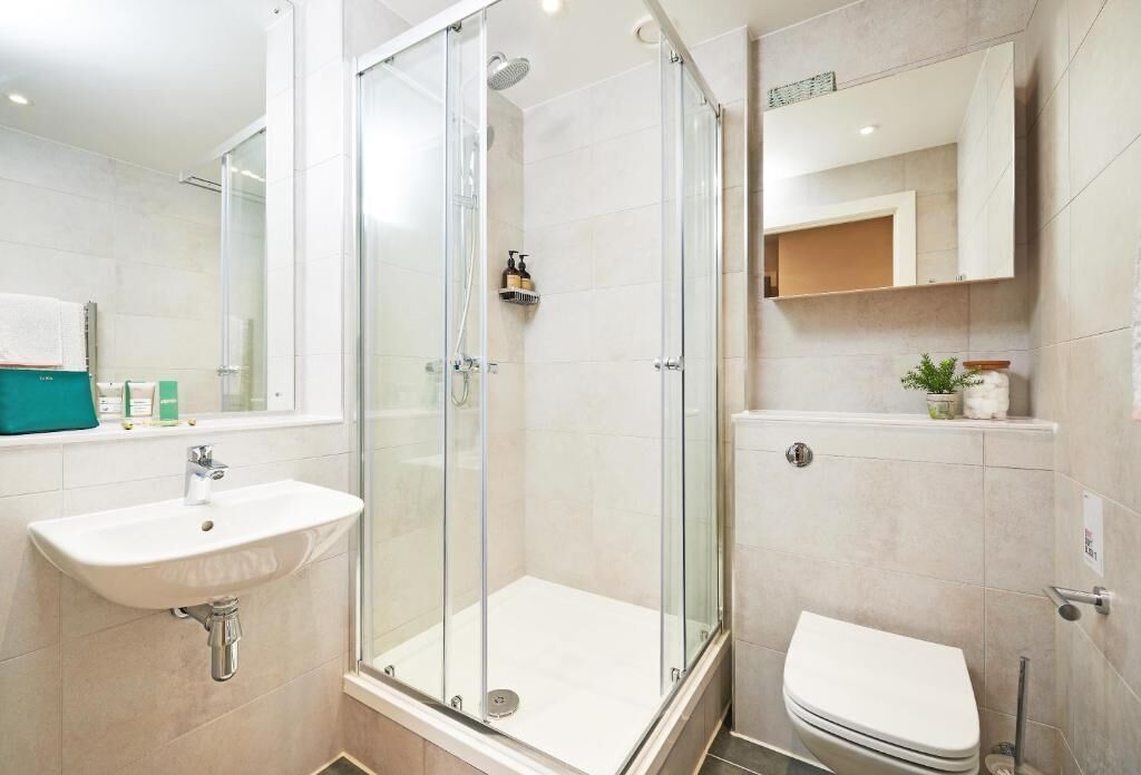 A modern bathroom with a glass-enclosed shower, a white sink, and a toilet.