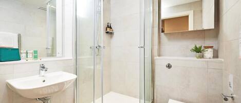 A modern bathroom with a glass-enclosed shower, a white sink, and a toilet.