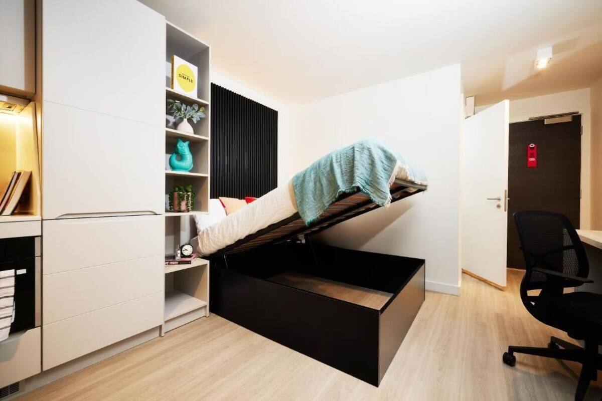 A compact room with a bed, a desk, and storage units.